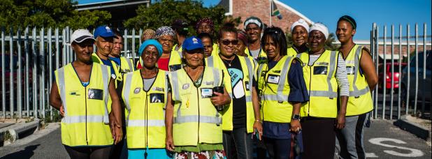 Group of black mothers and grandmothers dressed in high visibility jackets.