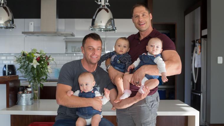 Two white men holding triplets