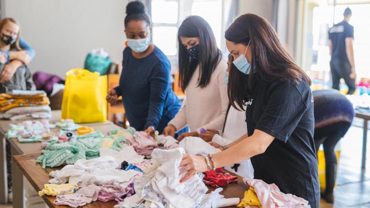 Beautiful News-Women sorting through clothes wearing masks.