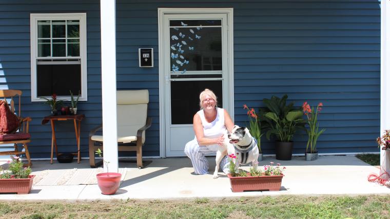 Beautiful News-Woman with dog in front of house.