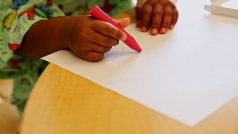 Beautiful News-Child holding a crayon.