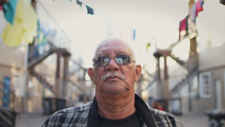 Old coloured man standing in between blocks of flats.