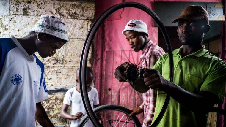 Black man inspecting bicycle wheel.