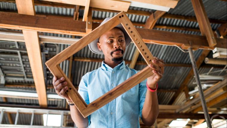 Black man holding wooden frame.