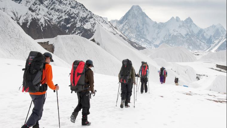 Mountaineers walking over snowy plains.