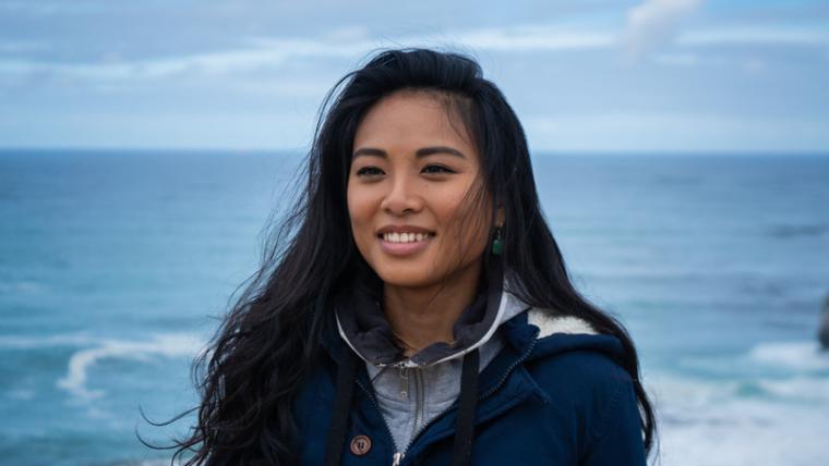 Asian woman smiles in front of the ocean