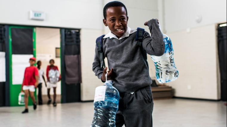 Black boy carrying 2 water bottles