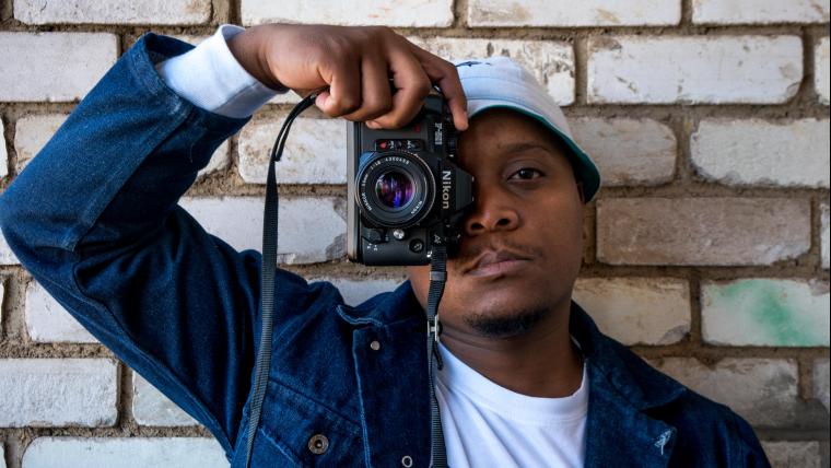 Man looks at the camera while covering one eye with a camera