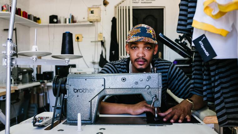 Fashion designer sitting behind his sewing machine.