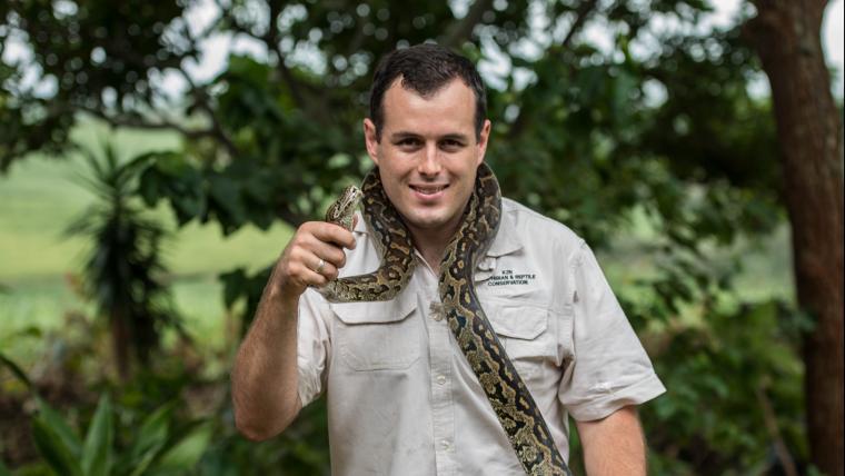 Man smiling with a snake around his shoulders