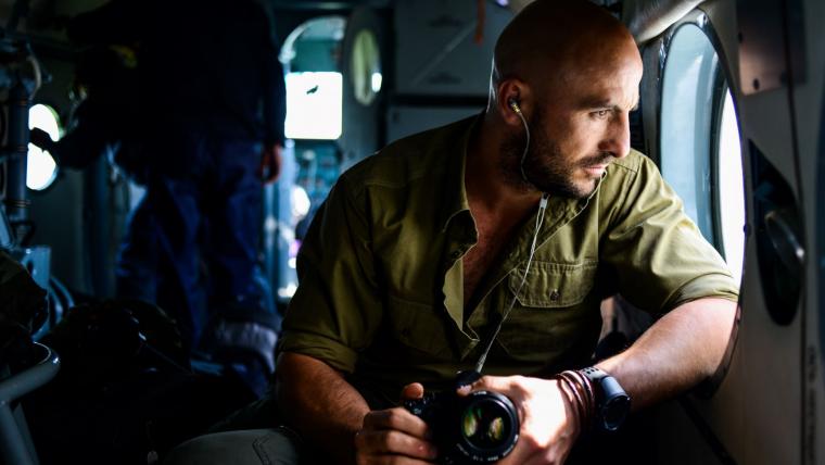 White man looking out helicopter window.