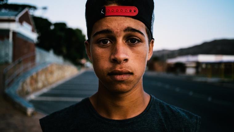 Young coloured boy and parkour performer wearing cap.