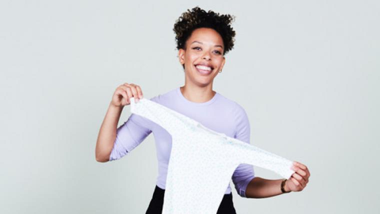 Woman holding baby clothes.