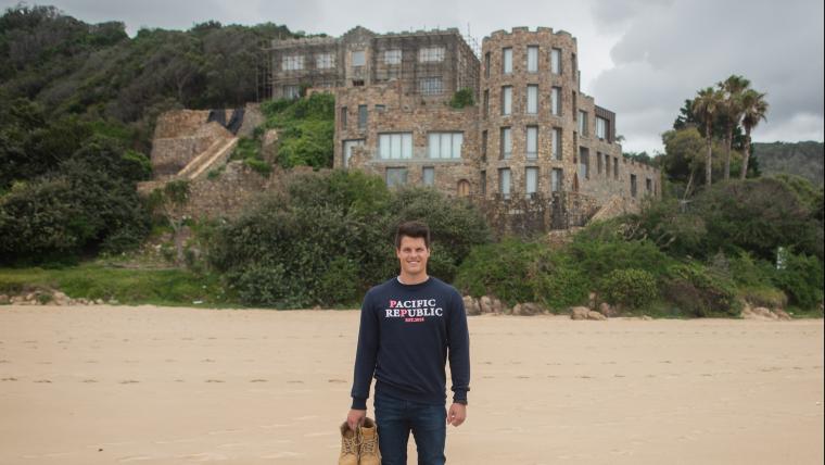 Man stands on a beach in front of a castle