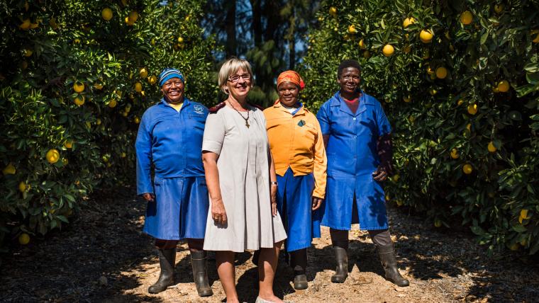 Four women stand surrounded by lemon trees