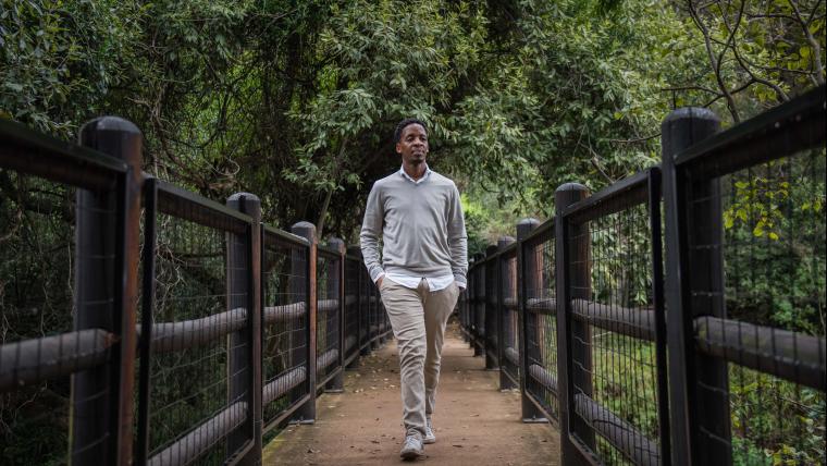 Man walks on a bridge through a forest