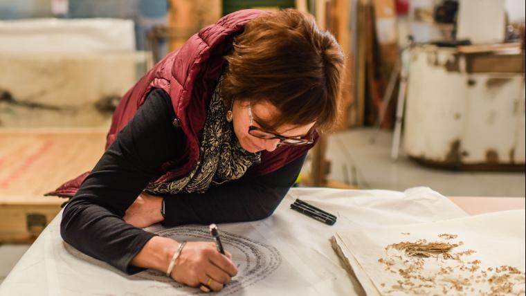 Woman leans on a table and sketches 