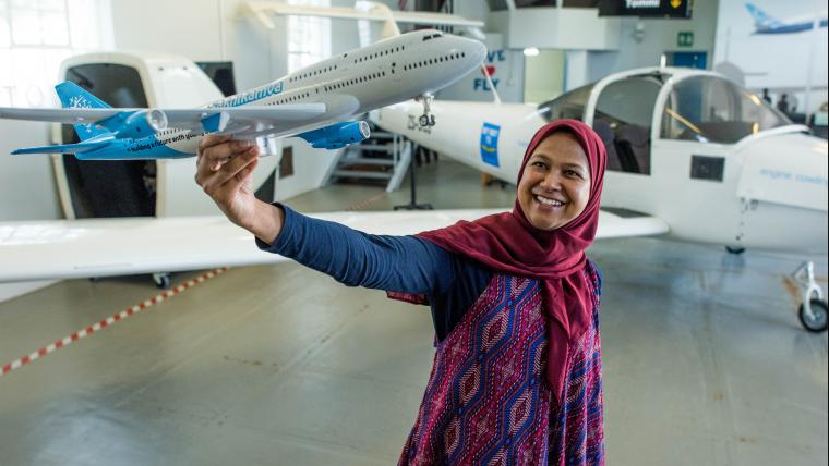 Muslim flight instructor holding model airplane.