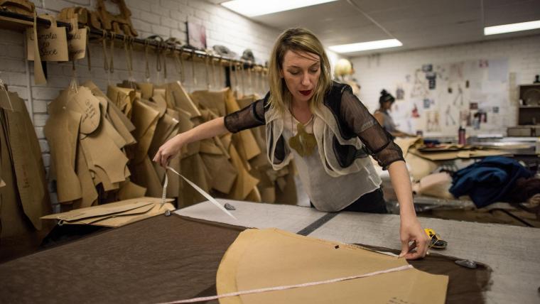 White woman measuring fabric with a tape measure