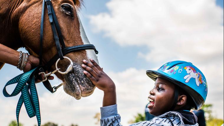 Differently abled boy caressing horse