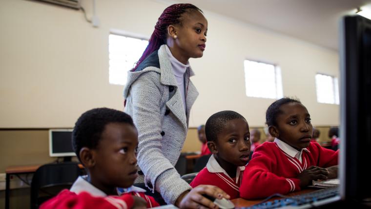 Teacher showing students how to use a computer