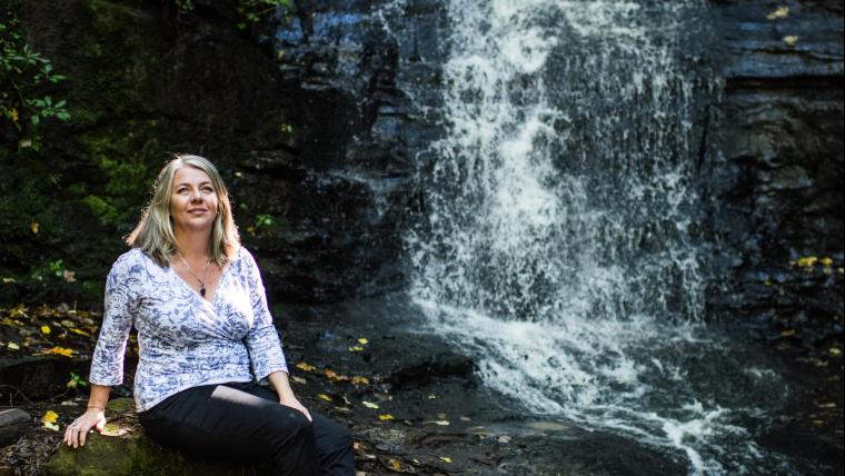 Woman sits next to a waterfall