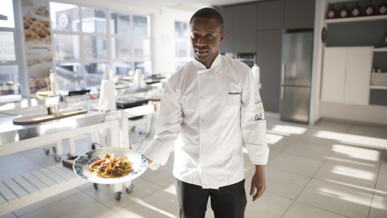 Black chef holding a plate