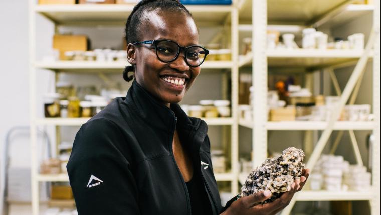 Woman holding shell, smiling at camera