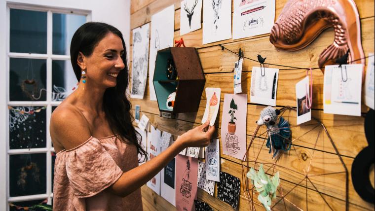 Woman smiles while looking at a wall of artwork