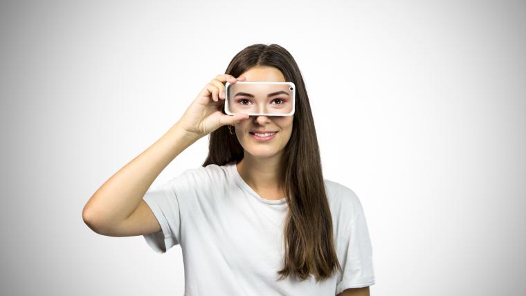 Women holding phone to her eyes. 