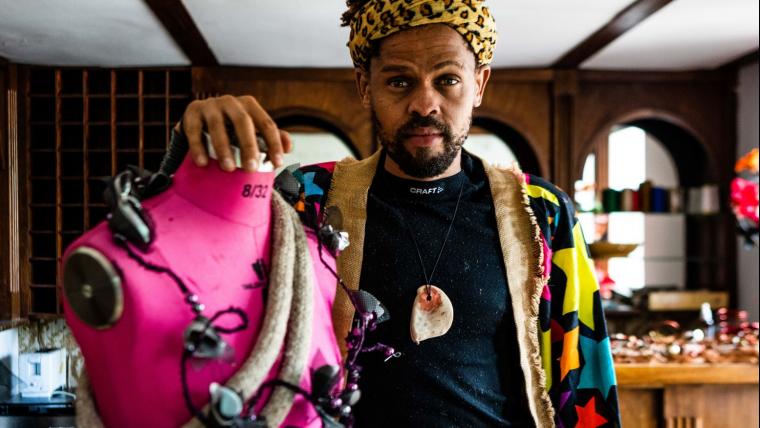 Black fashion designer standing by a mannequin.