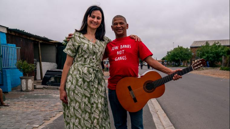 2 people. One holding a guitar