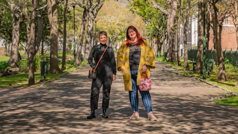 Beautiful News-Two women standing side by side on a walkway 