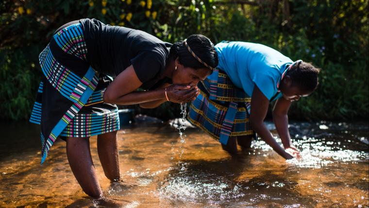 Women drinking out of a river. 