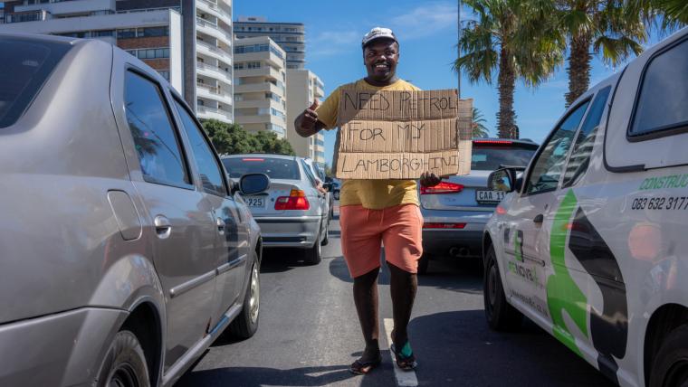 Beautiful News-Man holding humorous sign in traffic. 