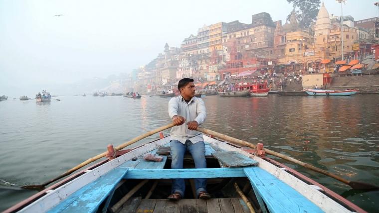 Beautiful News - Varanasi India, man peacefully rowing with city in background