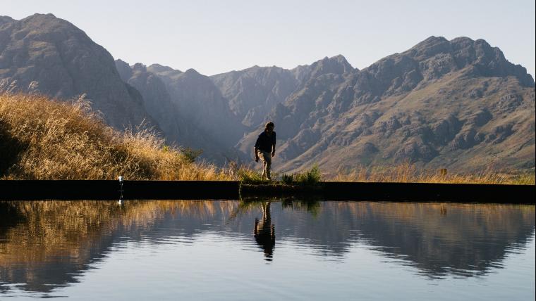 Man standing over a dam in the mountains