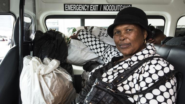 Black woman in taxi sitting next to bagged food for community.