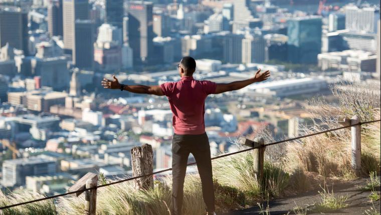 Man stands with his arms outstretched overlooking Cape Town