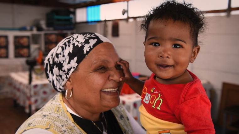 Coloured woman and child smiling into camera.