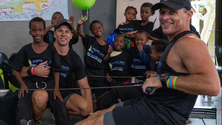 Man stationary rowing with kids in background.