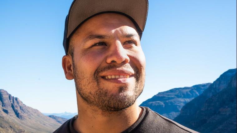 Man smiles and looks off into the distance with mountains in the background