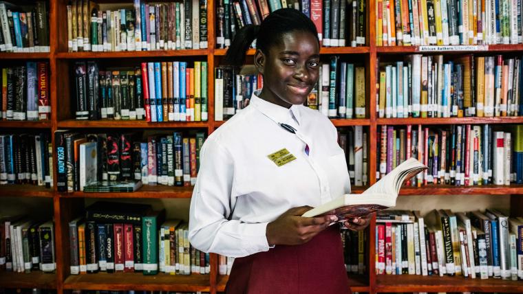 Black girl smiling in front of books