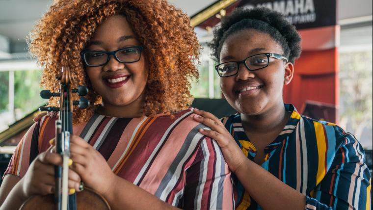 2 young women. One holding a violin