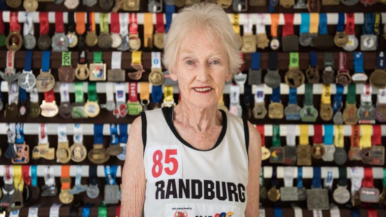 Old woman smiling in front of medals