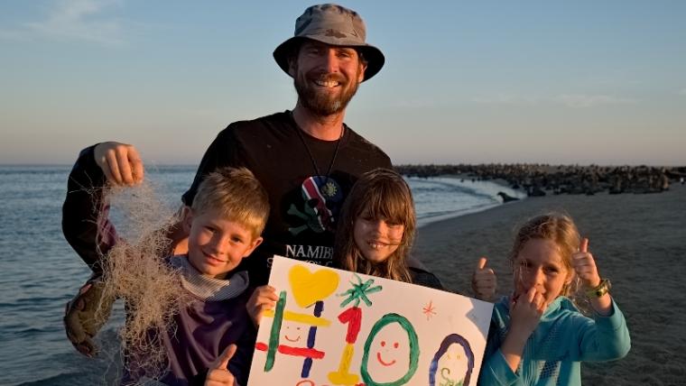 men and kids holding up a sign. 