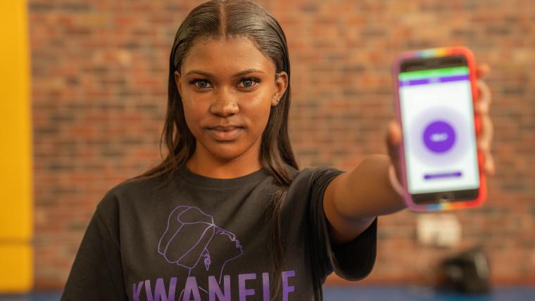 Social worker Onele Nobongoza holds up a cellphone displaying the Kwanele South Africa app