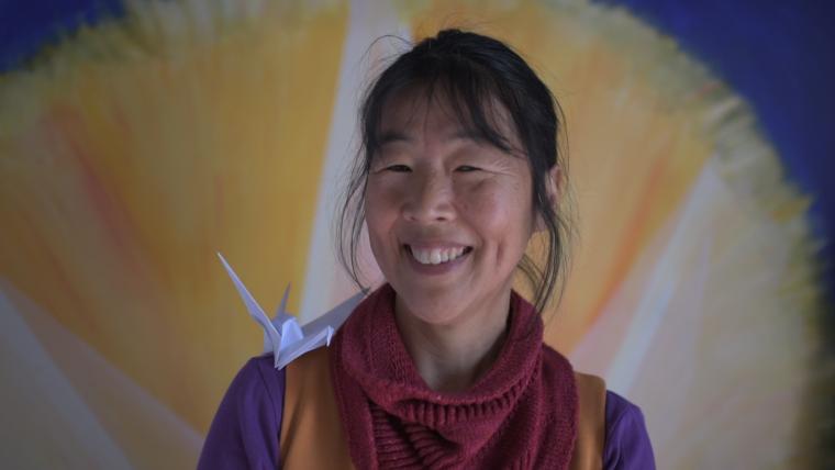 Asian woman with origami art on her shoulder.