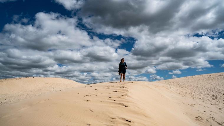 Woman walking on sand dune