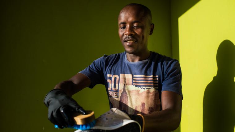 Black man washing a shoe.